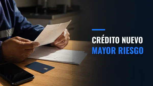 Un trabajador revisa documentos financieros junto a una tarjeta bancaria y un teléfono, con el llamado Crédito nuevo, mayor riesgo.